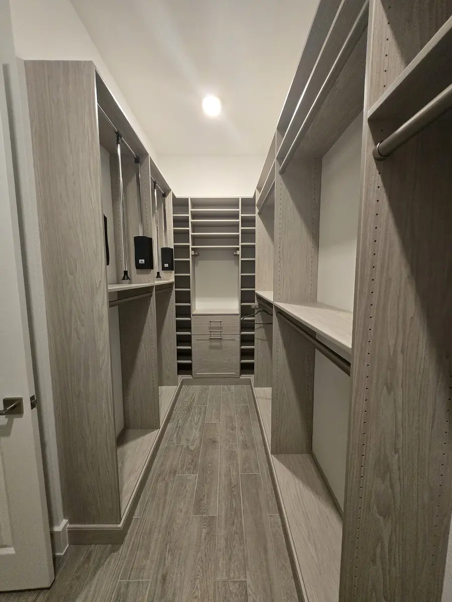 Installed walk-in closet system with hanging rails and shoe shelving