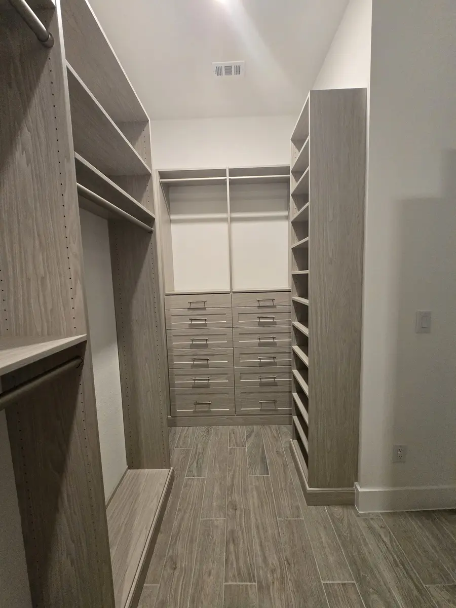 Installed walk-in closet system with hanging rails and shoe shelving