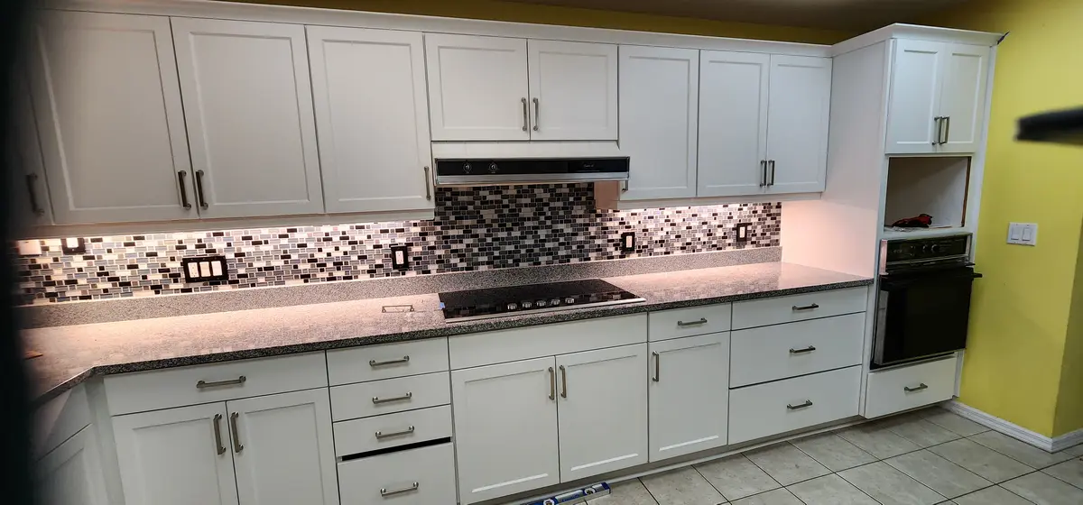 Installed kitchen cabinets with upper and base runs and a tile backsplash