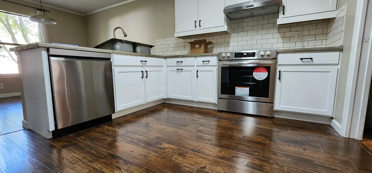 Installed kitchen cabinets with upper and base runs and a tile backsplash