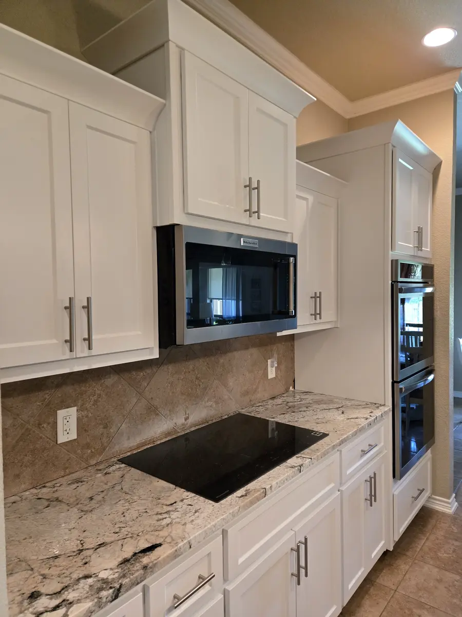 Installed kitchen cabinets with upper and base runs and a tile backsplash