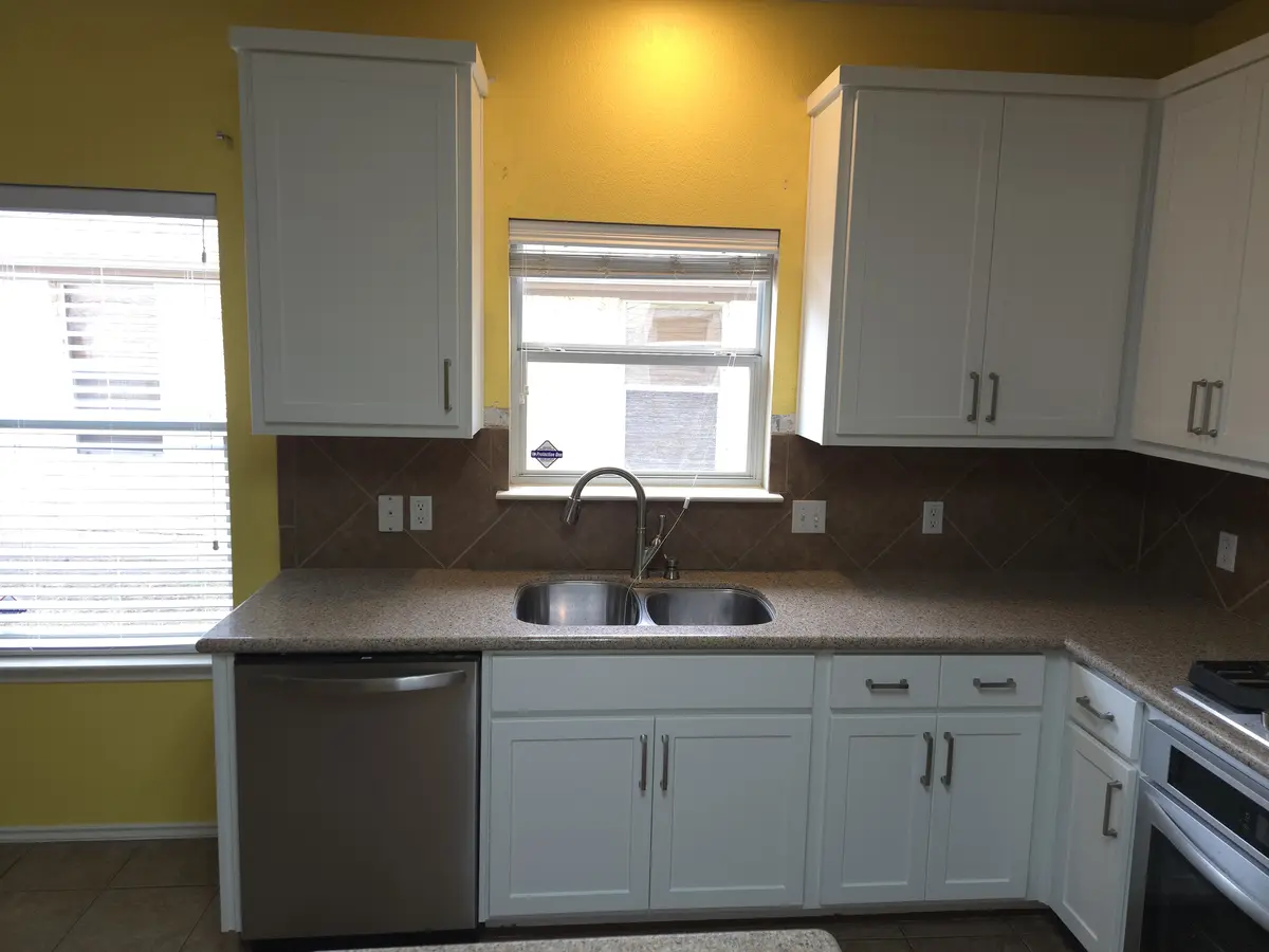 Installed kitchen cabinets with upper and base runs and a tile backsplash