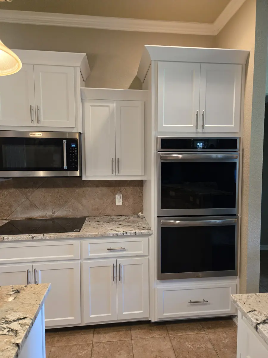 Installed kitchen cabinets with upper and base runs and a tile backsplash